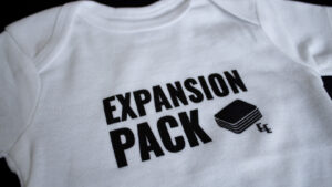 A photo showing a baby onesie with the phrase Expansion Pack.